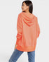 Woman wearing a coral hoodie and blue jeans on a white background