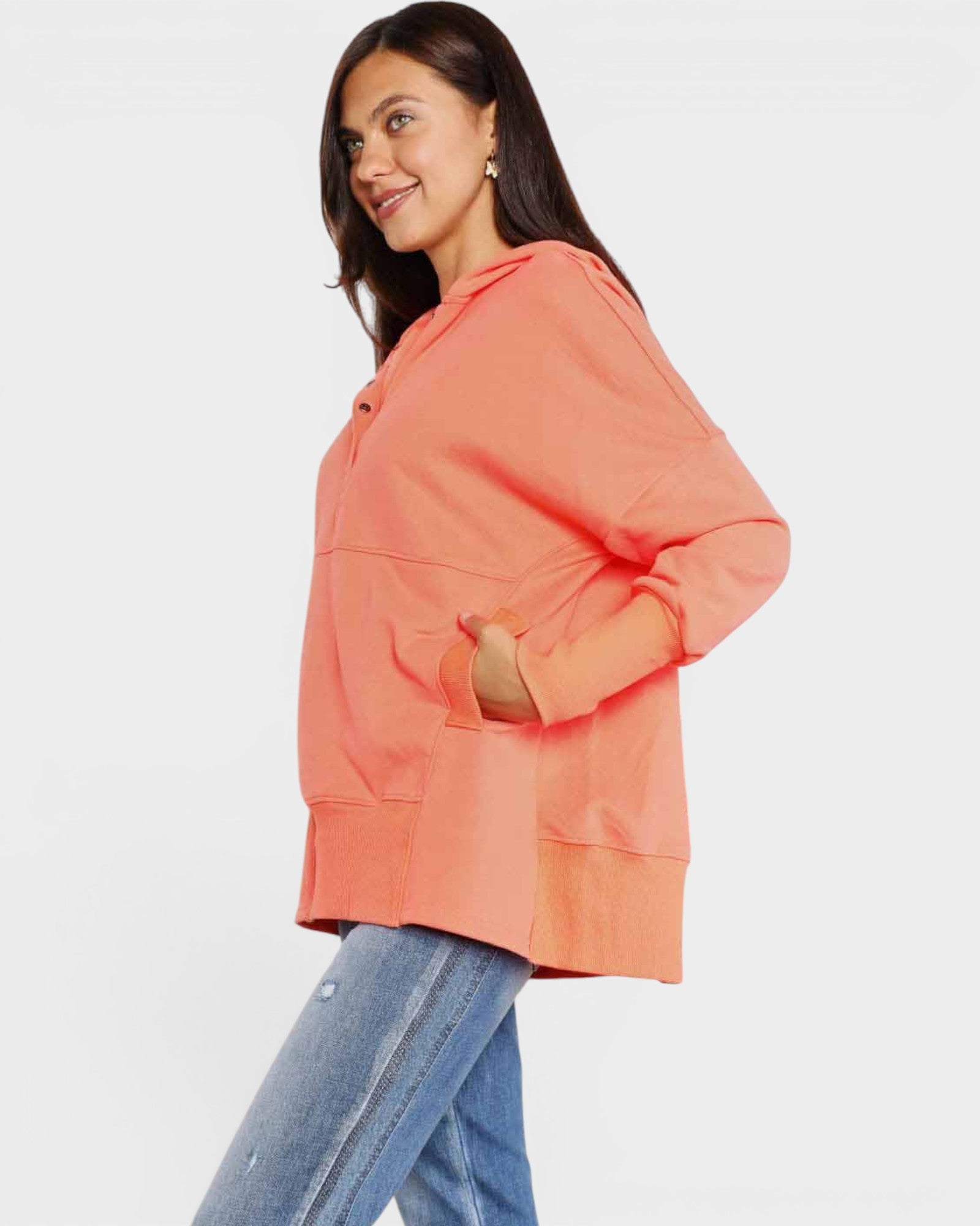 Woman wearing an orange jacket and blue jeans on a white background