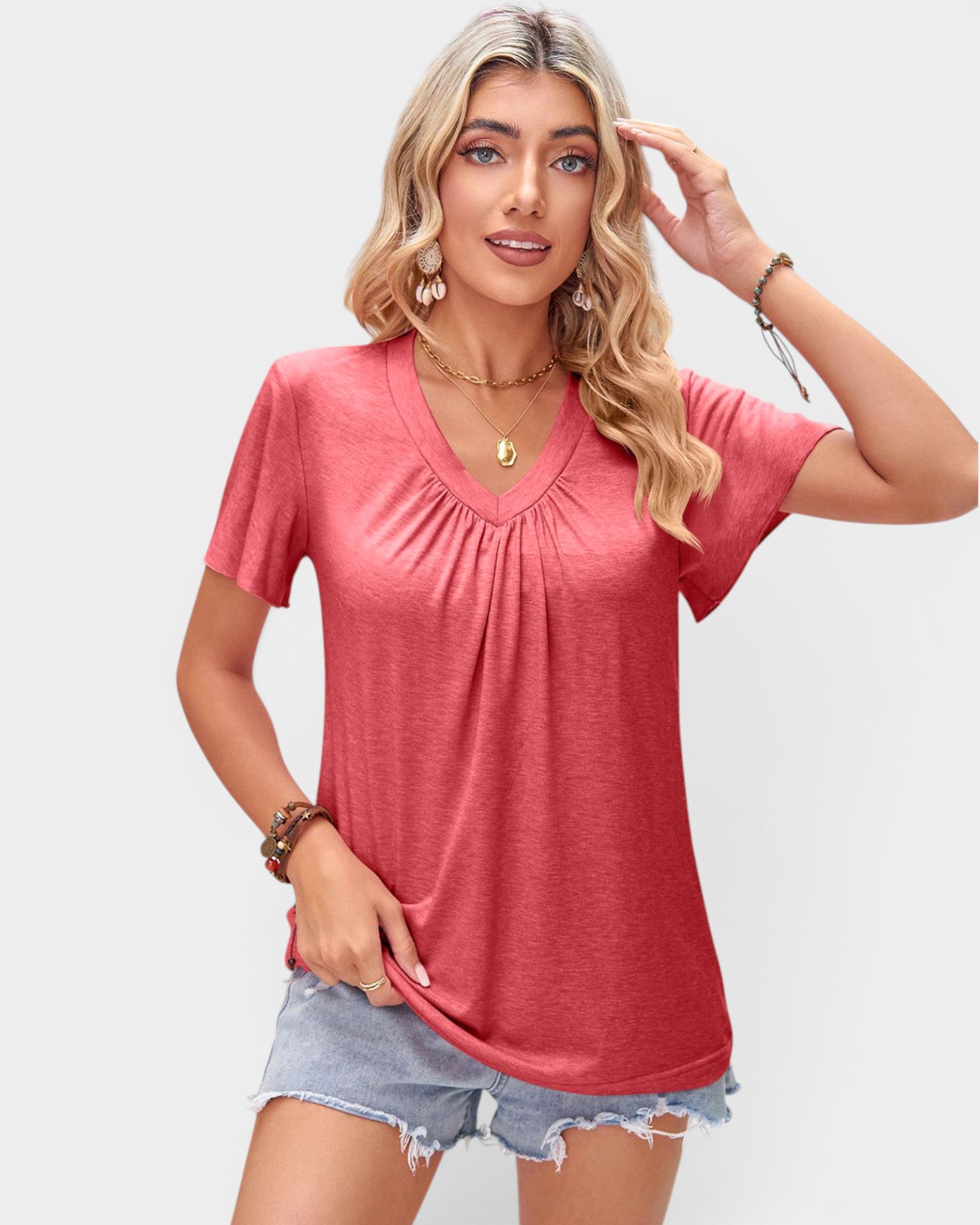 Woman wearing a pink short-sleeve top and denim shorts on a plain background
