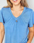 Woman wearing a blue shirt with a heart-shaped pendant necklace on a plain background