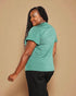 Woman wearing a green t-shirt and black pants against a beige background