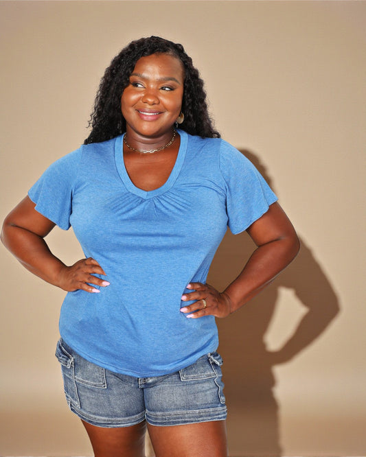 Woman wearing a blue t-shirt and denim shorts against a beige background