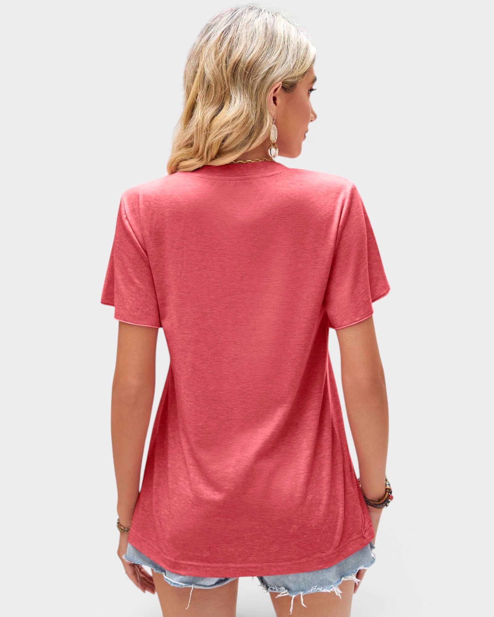 Person wearing a pink t-shirt and denim shorts on a plain background