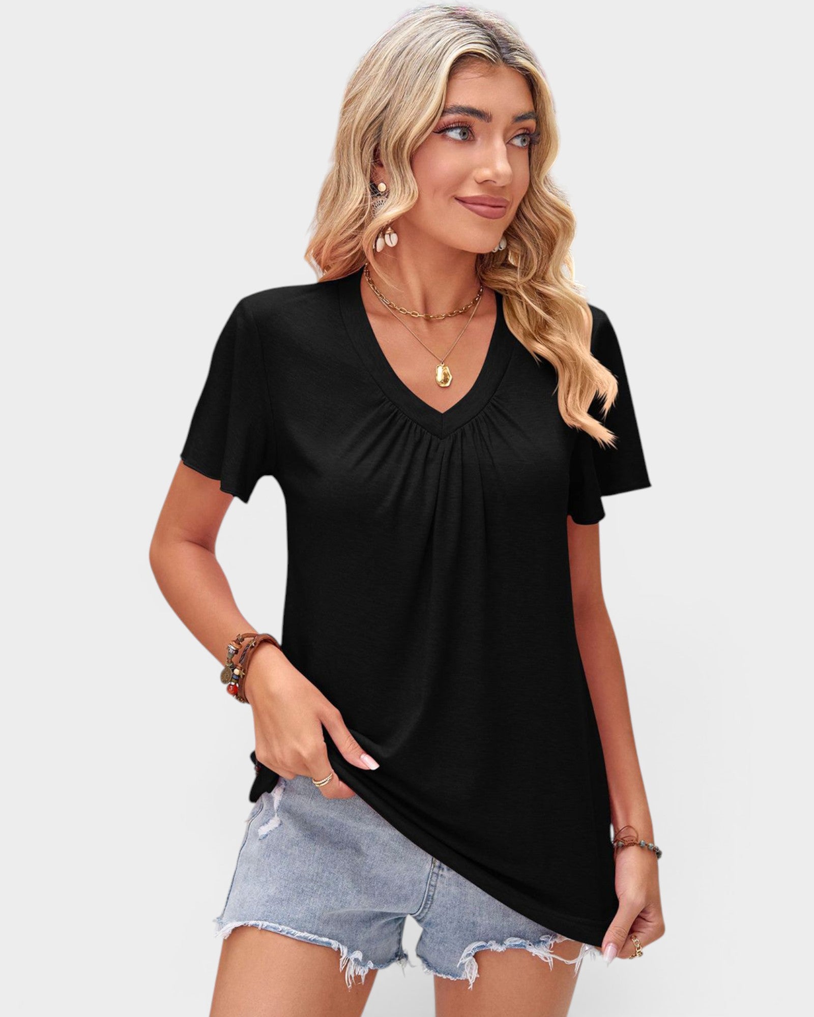 Woman wearing a black V-neck t-shirt and denim shorts on a plain background