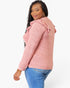 A woman wearing a heathered pink long-sleeve top with ruffled shoulder details, paired with blue jeans, photographed against a clean white background.