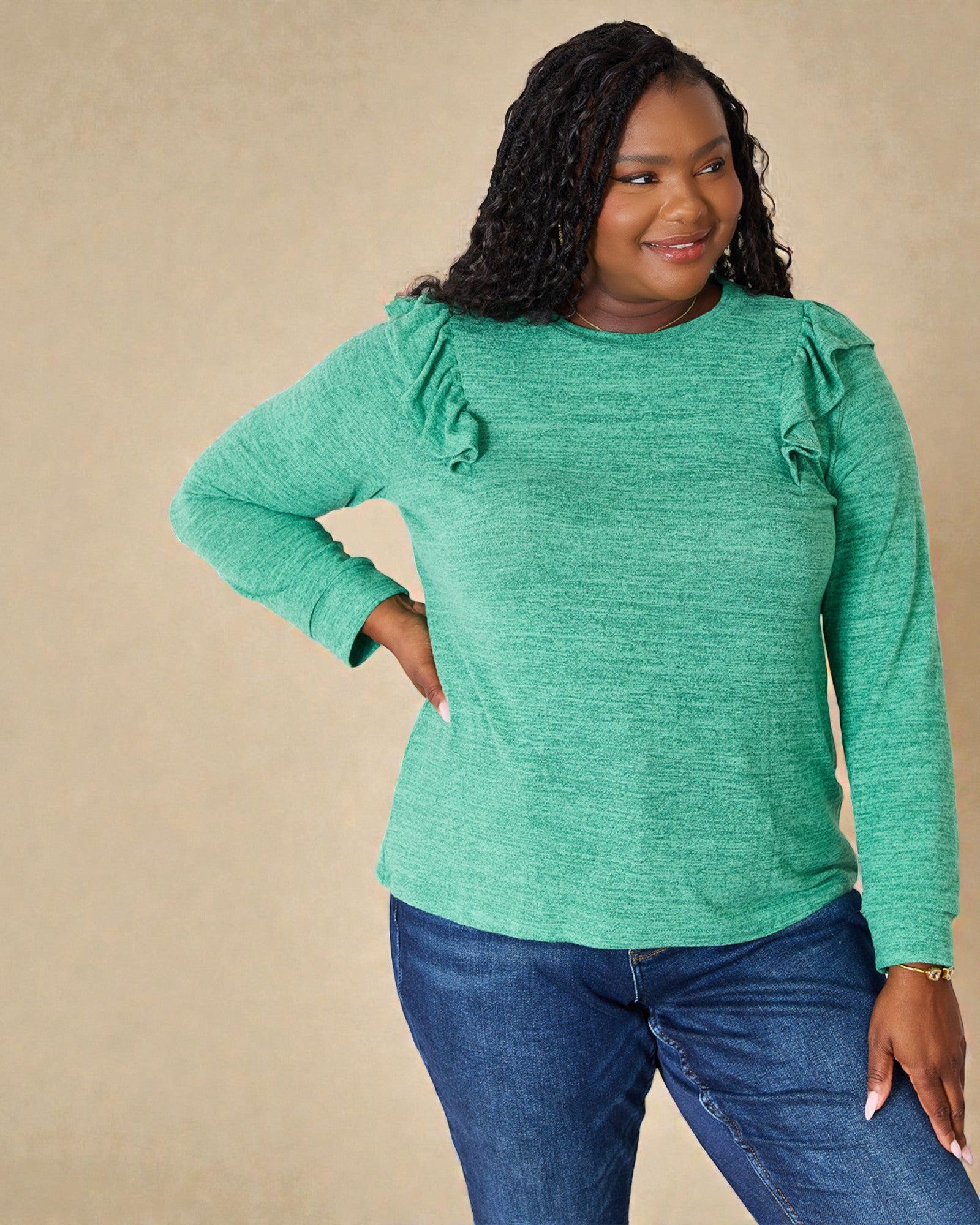 Woman wearing a green sweater with ruffled sleeves against a beige background
