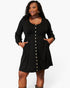 A plus-size woman modeling a black long-sleeve mini dress with a button-down front and side pockets, set against a plain light gray studio background.