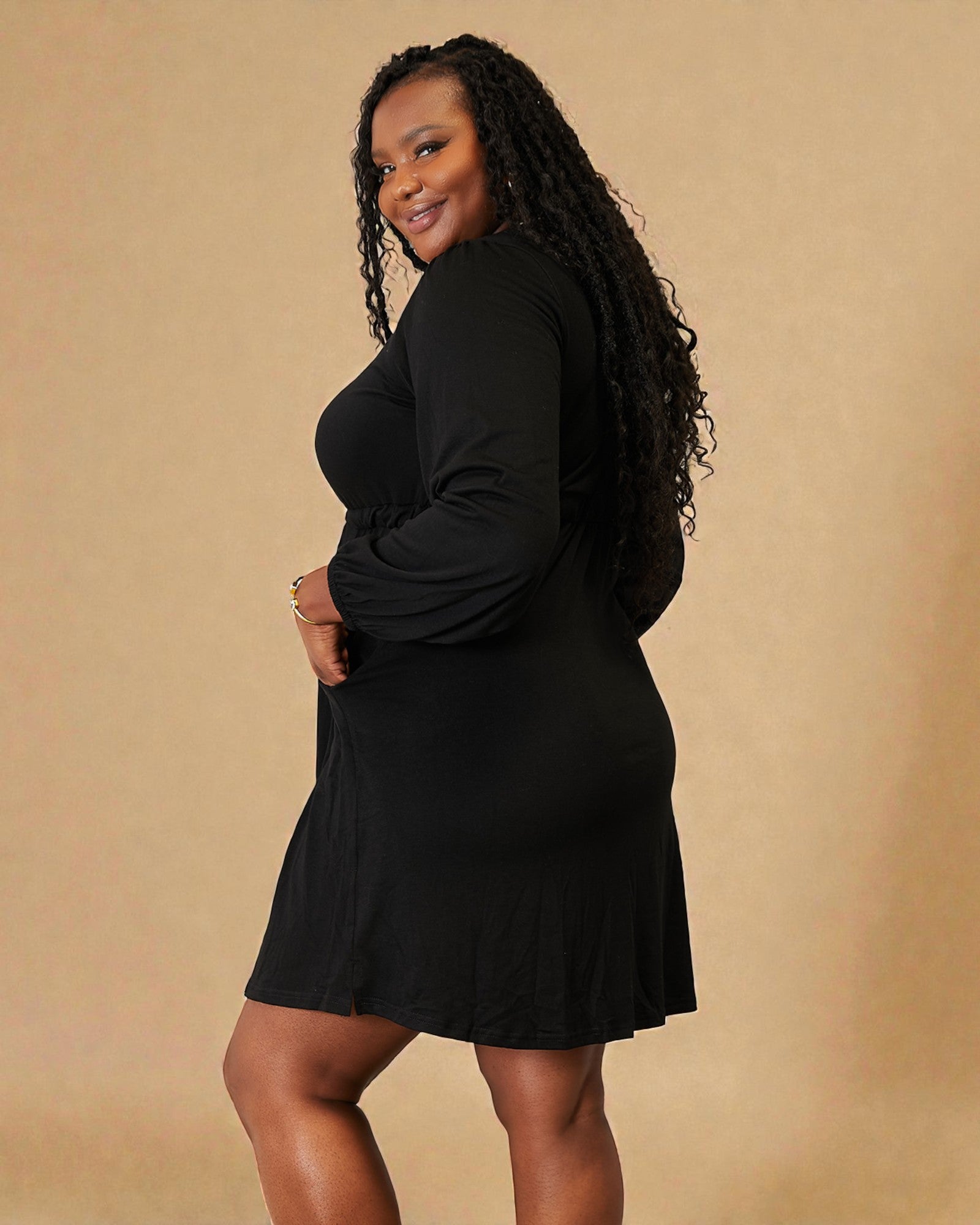 Woman wearing a black dress against a beige background