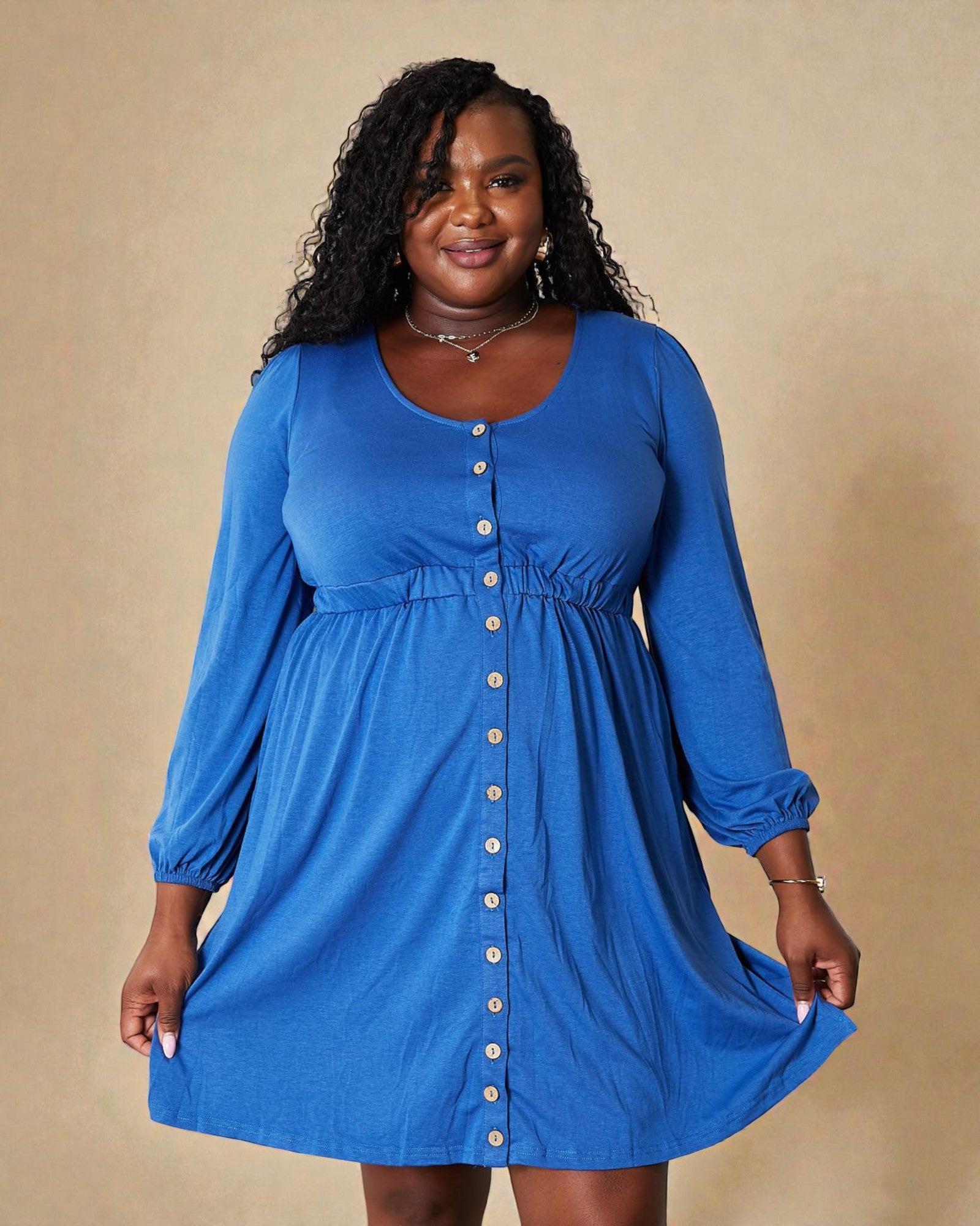 Woman wearing a blue dress with buttons on a beige background