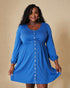 Woman wearing a blue dress with buttons on a beige background