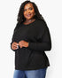 A woman modeling a black long-sleeve crewneck top with a relaxed fit, paired with blue jeans, against a plain white studio background.