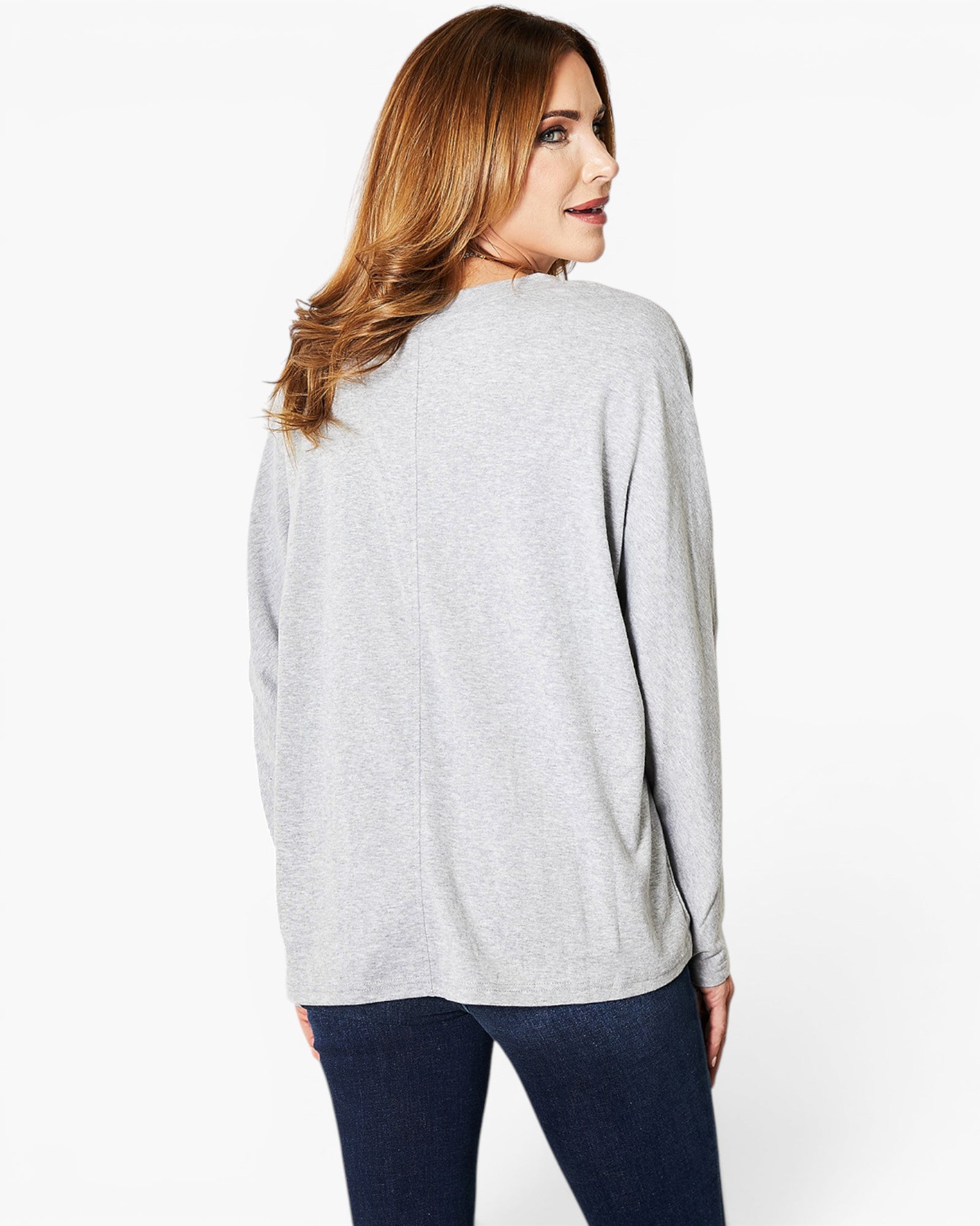 A woman shown from the back wearing a light gray heathered long-sleeve top and dark blue jeans, photographed against a clean white studio background.