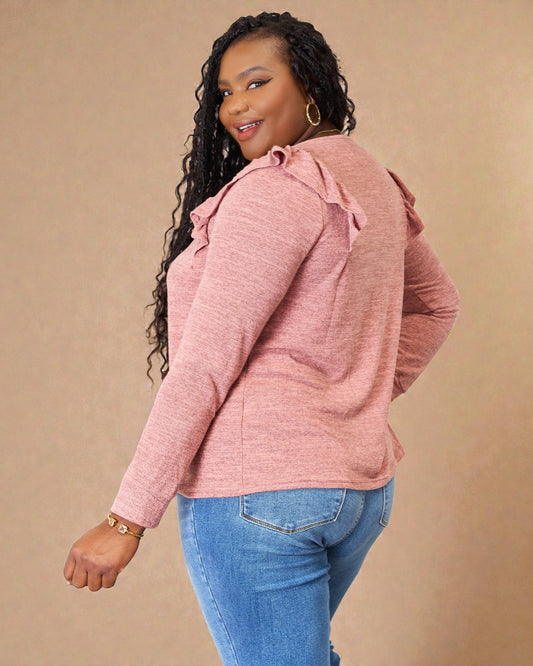 Woman wearing a pink textured sweater with ruffled shoulders against a beige background