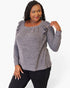 A woman modeling a heather gray long-sleeve top with ruffled shoulder details, paired with black pants, against a plain white background.