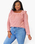 A woman modeling a dusty pink long-sleeve top with ruffled shoulder details and a square neckline, paired with blue jeans, against a plain white background.