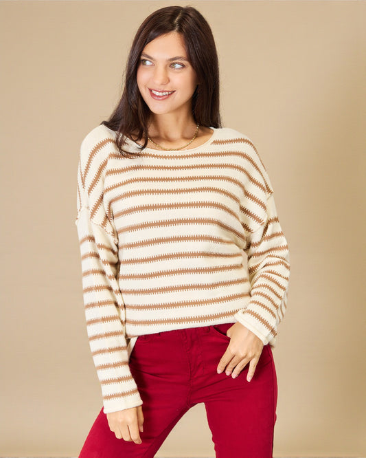 Woman wearing a striped sweater and red pants against a beige background