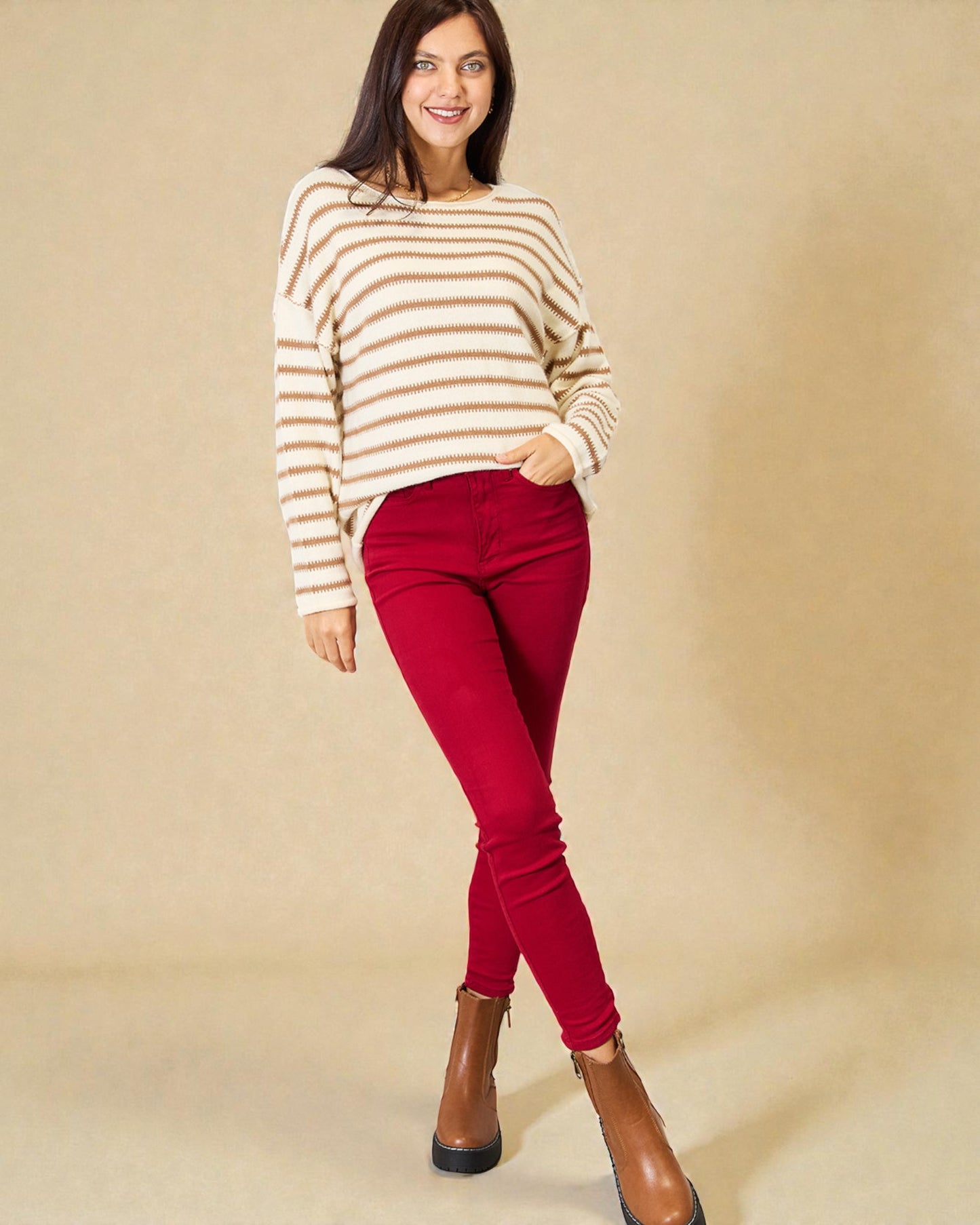 Woman wearing a striped sweater and red pants against a beige background