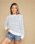 Woman wearing a striped sweater and denim shorts on a beige background