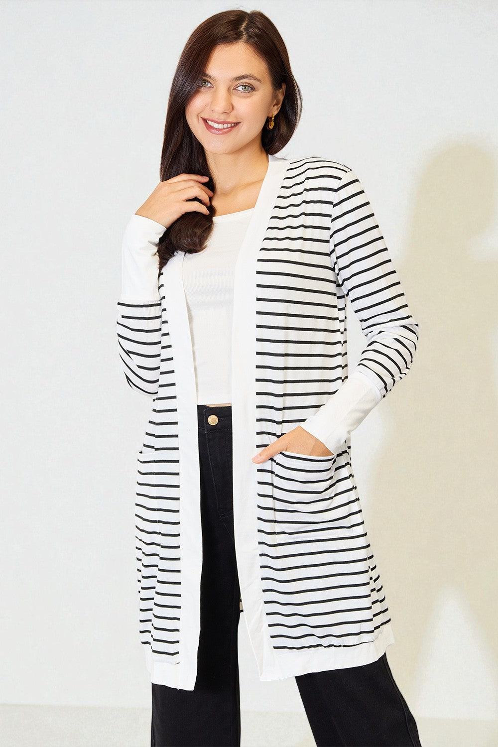 Woman wearing a long black and white striped cardigan over a white shirt.