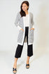 Woman wearing a black and white striped cardigan with black pants on a white background