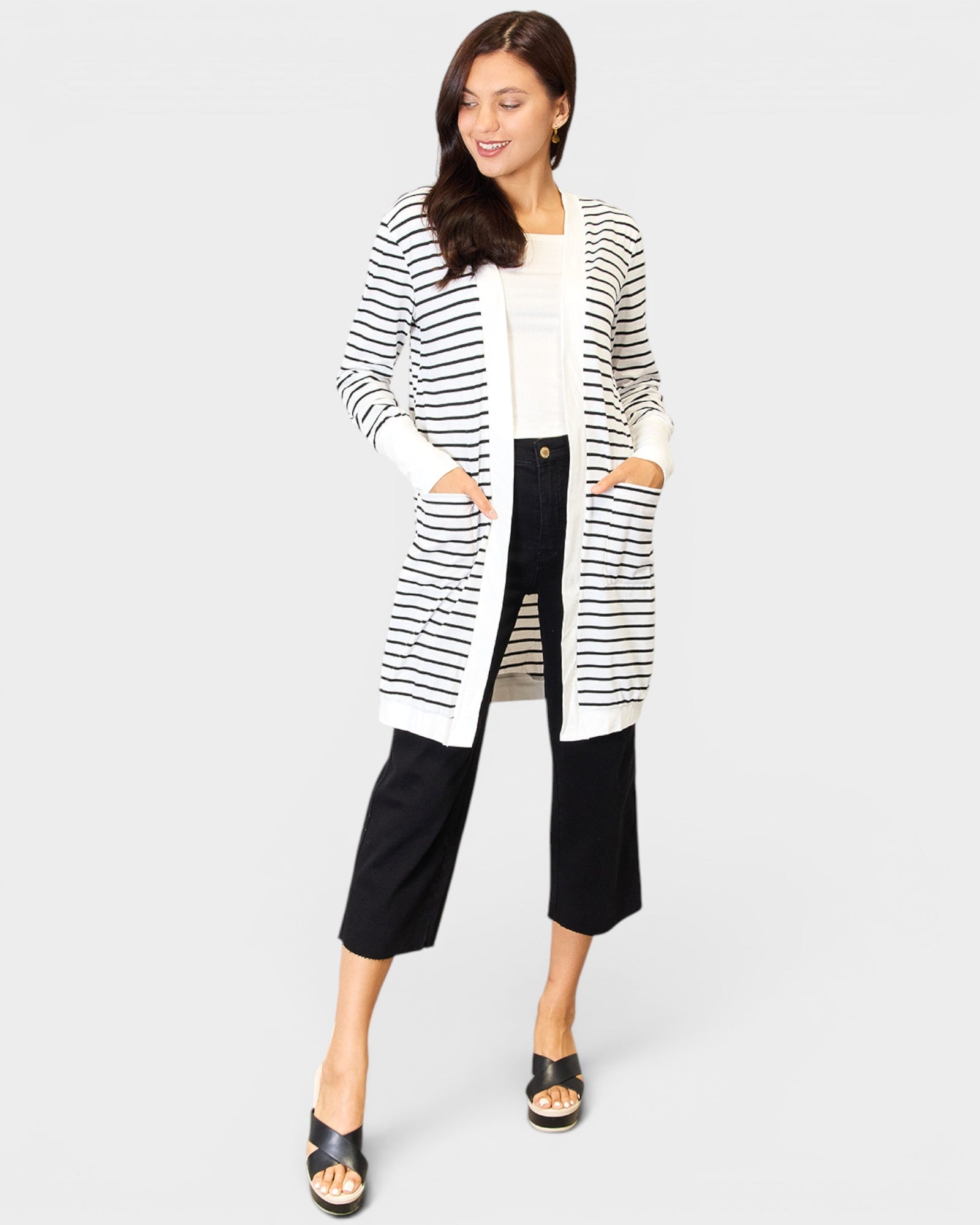 Woman wearing a long black and white striped cardigan on a white background