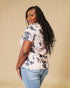 Woman wearing a tie-dye shirt and jeans against a beige background