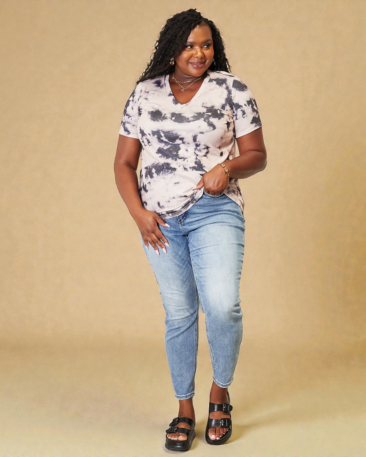 Woman wearing a tie-dye shirt and jeans on a beige background