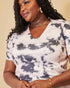 Woman wearing a tie-dye shirt with a neutral background
