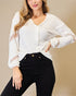 Woman wearing a white blouse with lace sleeves and black pants on a beige background