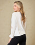 Woman wearing a white sweater with a subtle pattern on a beige background