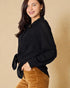 Woman wearing a black knitted cardigan over a brown outfit on a beige background