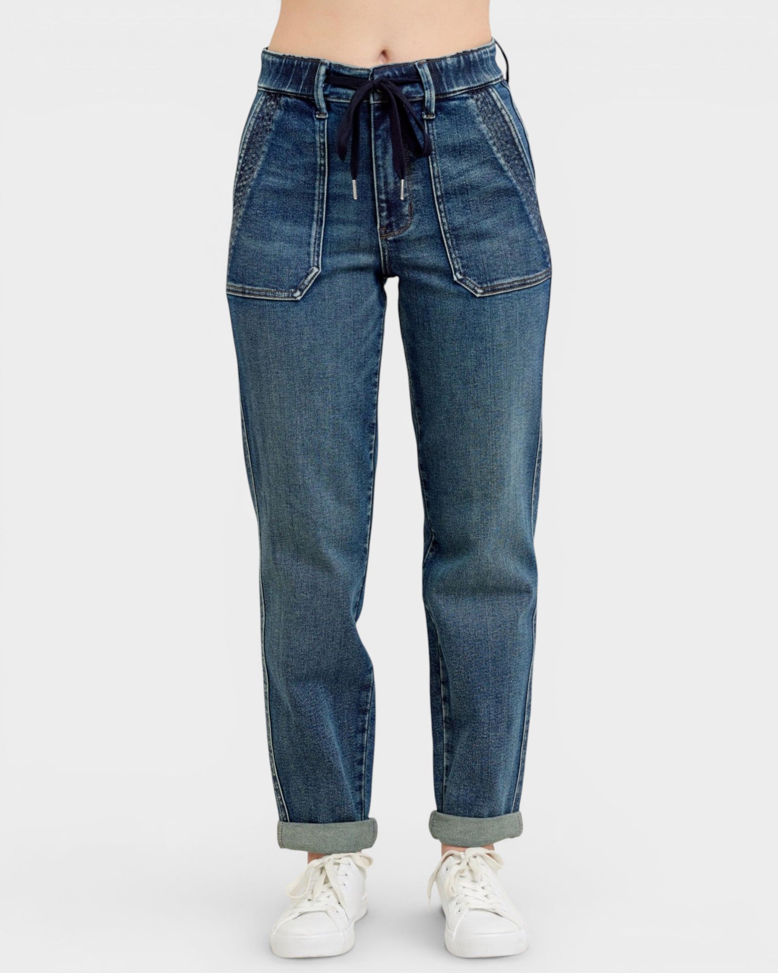Blue jeans worn with white sneakers on a white background