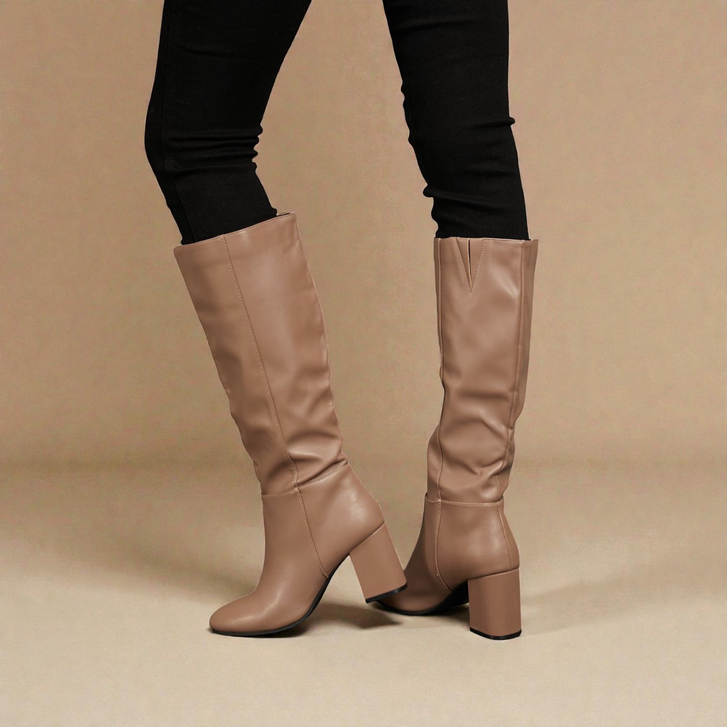 Beige knee-high boots worn with black leggings on a beige background