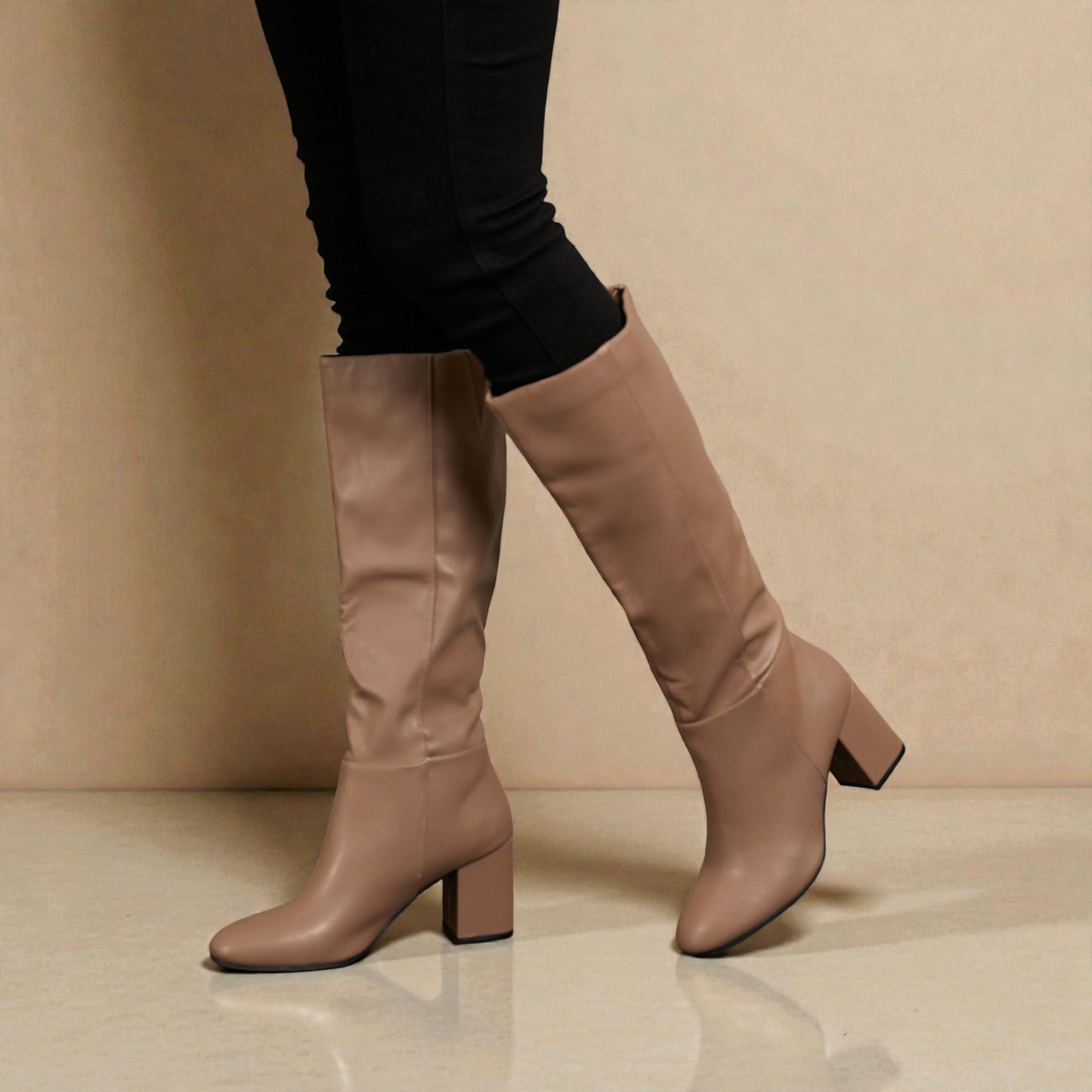 Beige knee-high boots worn with black leggings on a beige background