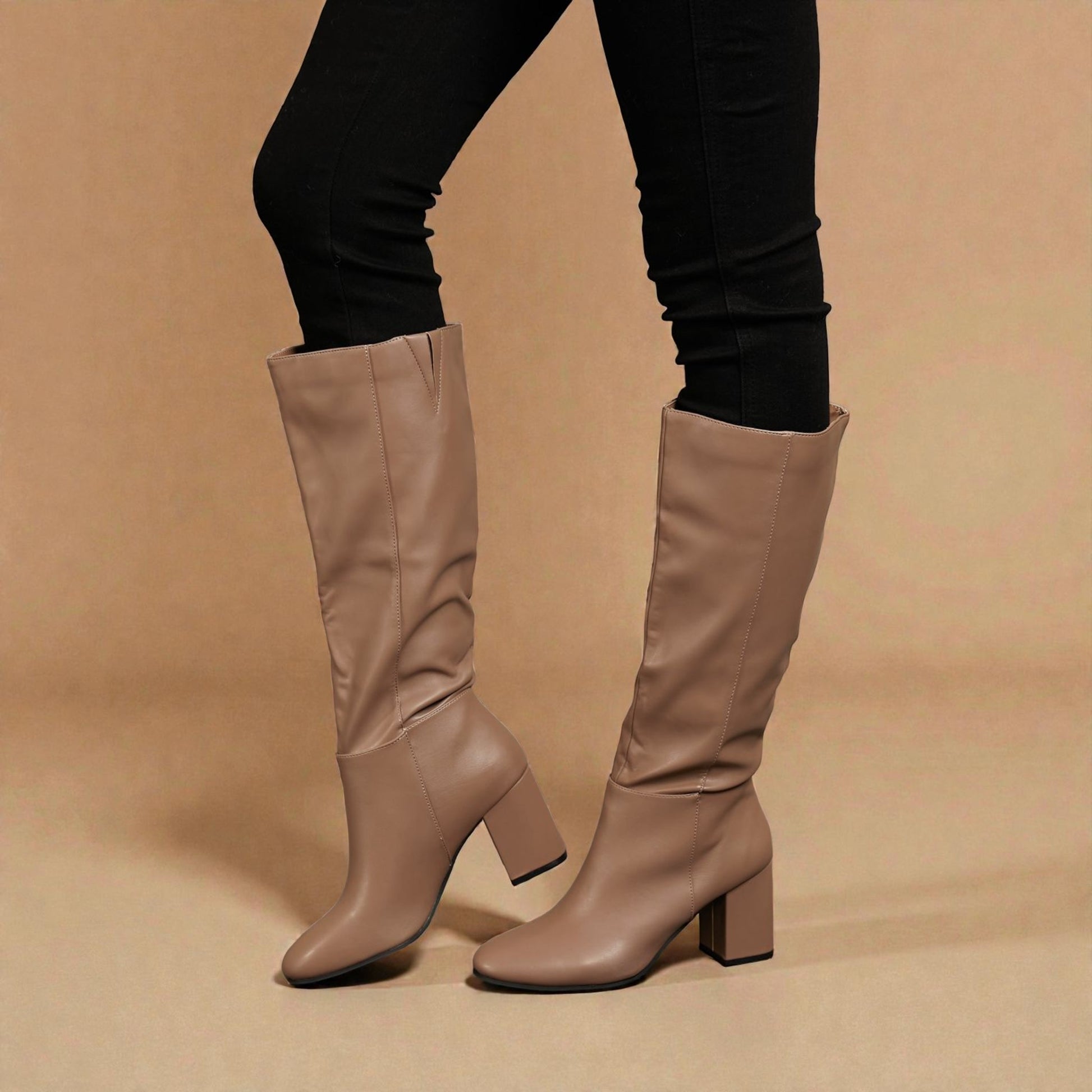Beige knee-high boots worn with black leggings on a beige background