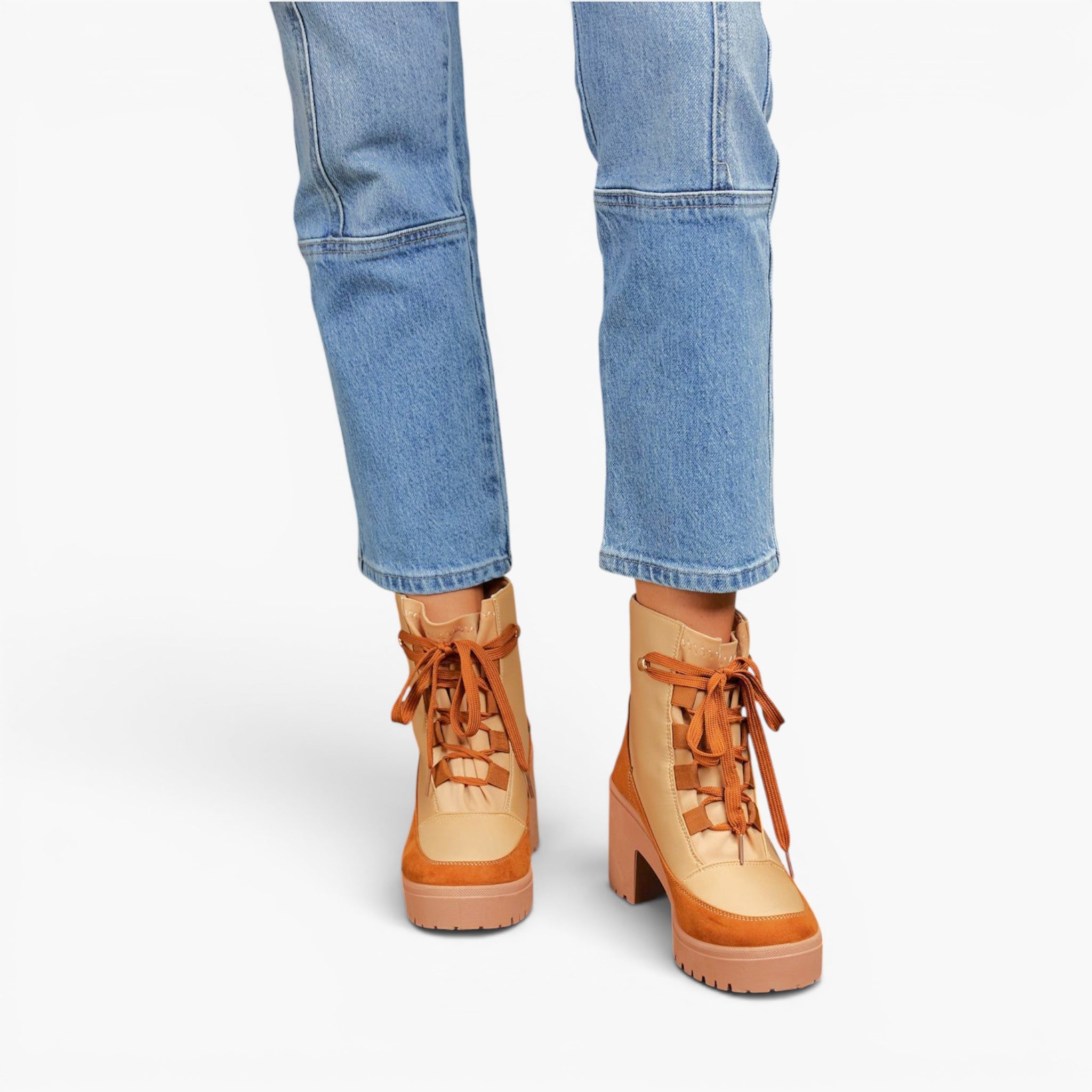 A person wearing light blue jeans and tan lace-up platform ankle boots against a clean white studio background.