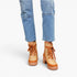 A person wearing light blue jeans and tan lace-up platform ankle boots against a clean white studio background.
