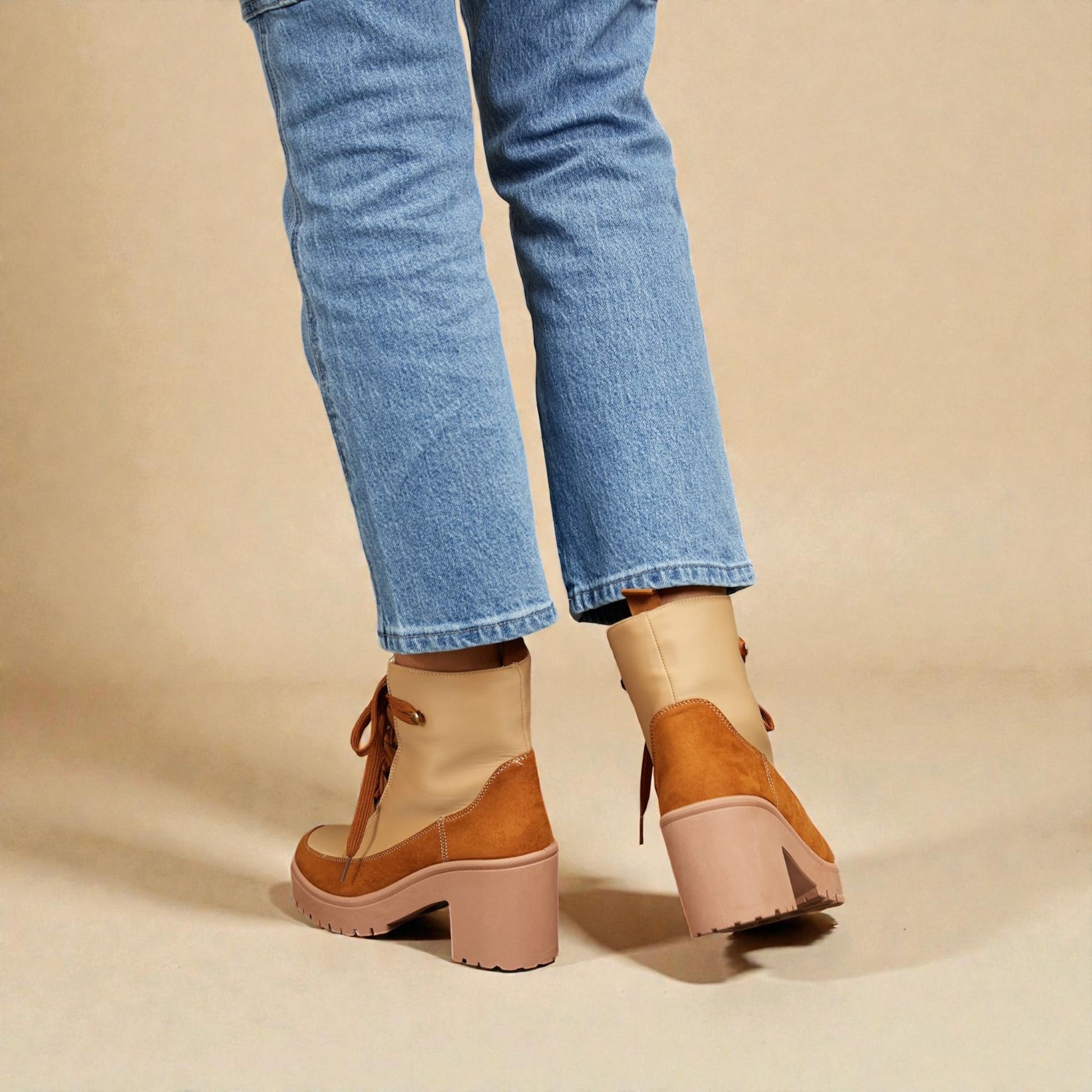 Brown platform shoes worn with blue jeans on a beige background