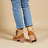 Brown platform shoes worn with blue jeans on a beige background