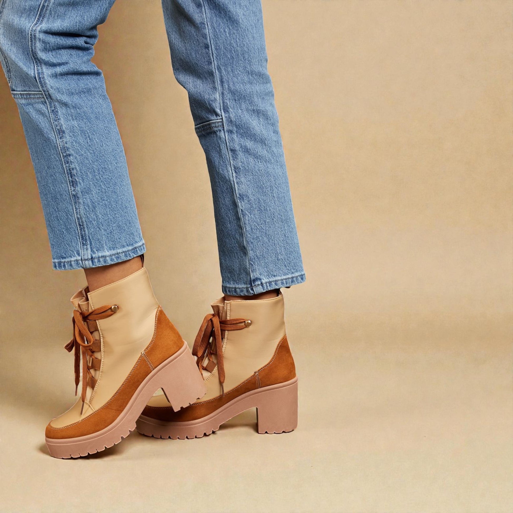 Beige and brown ankle boots worn with blue jeans on a beige background