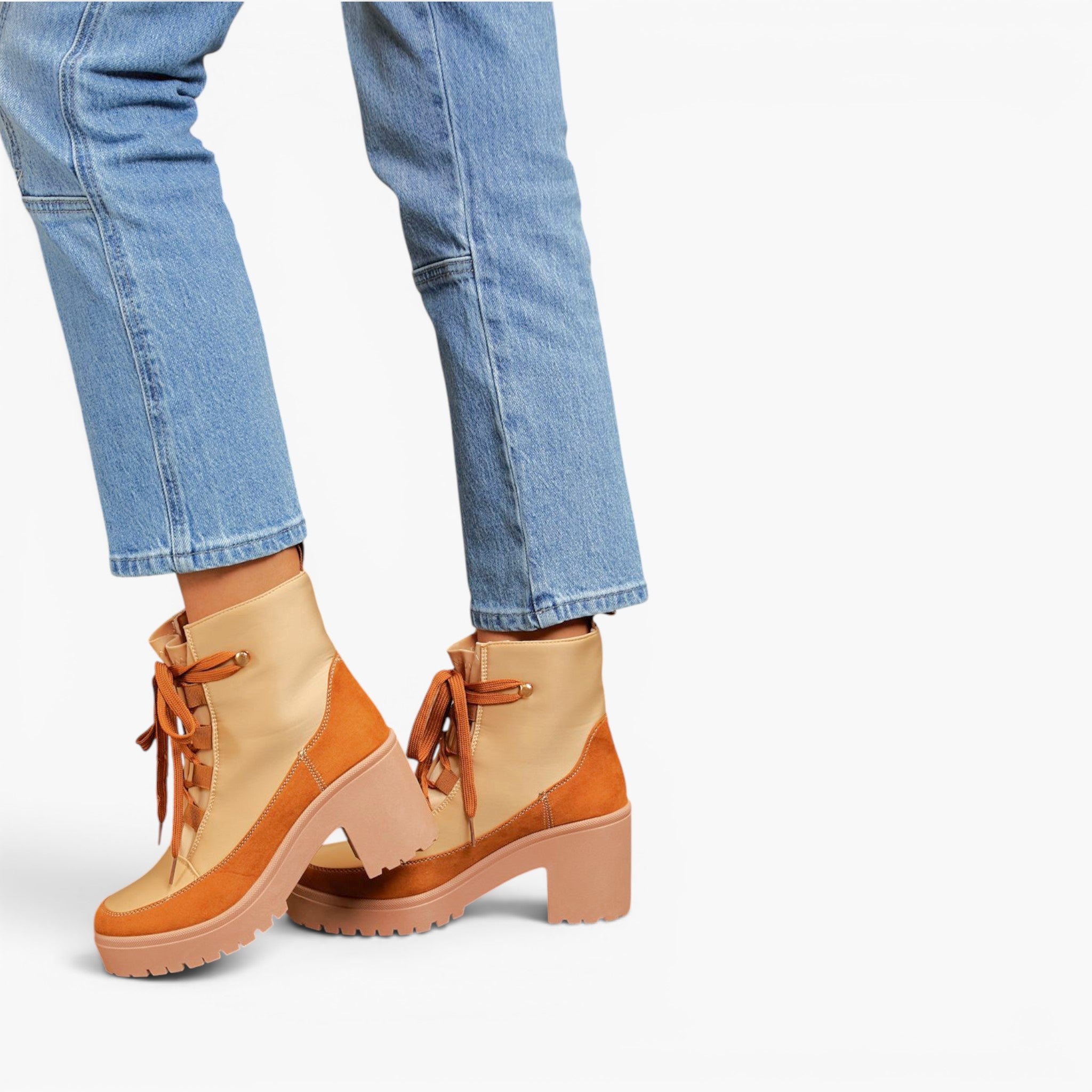 A pair of women's ankle boots in tan and light brown suede, styled with light-wash blue jeans against a plain white background.