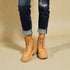 Tan combat boots worn with rolled-up jeans on a beige background