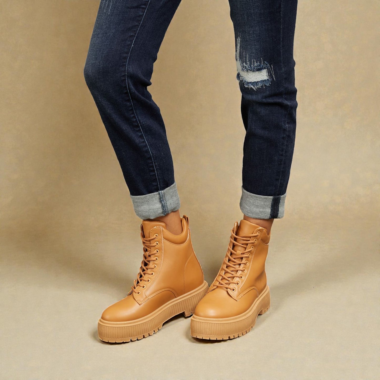 Tan boots worn with dark jeans on a beige background