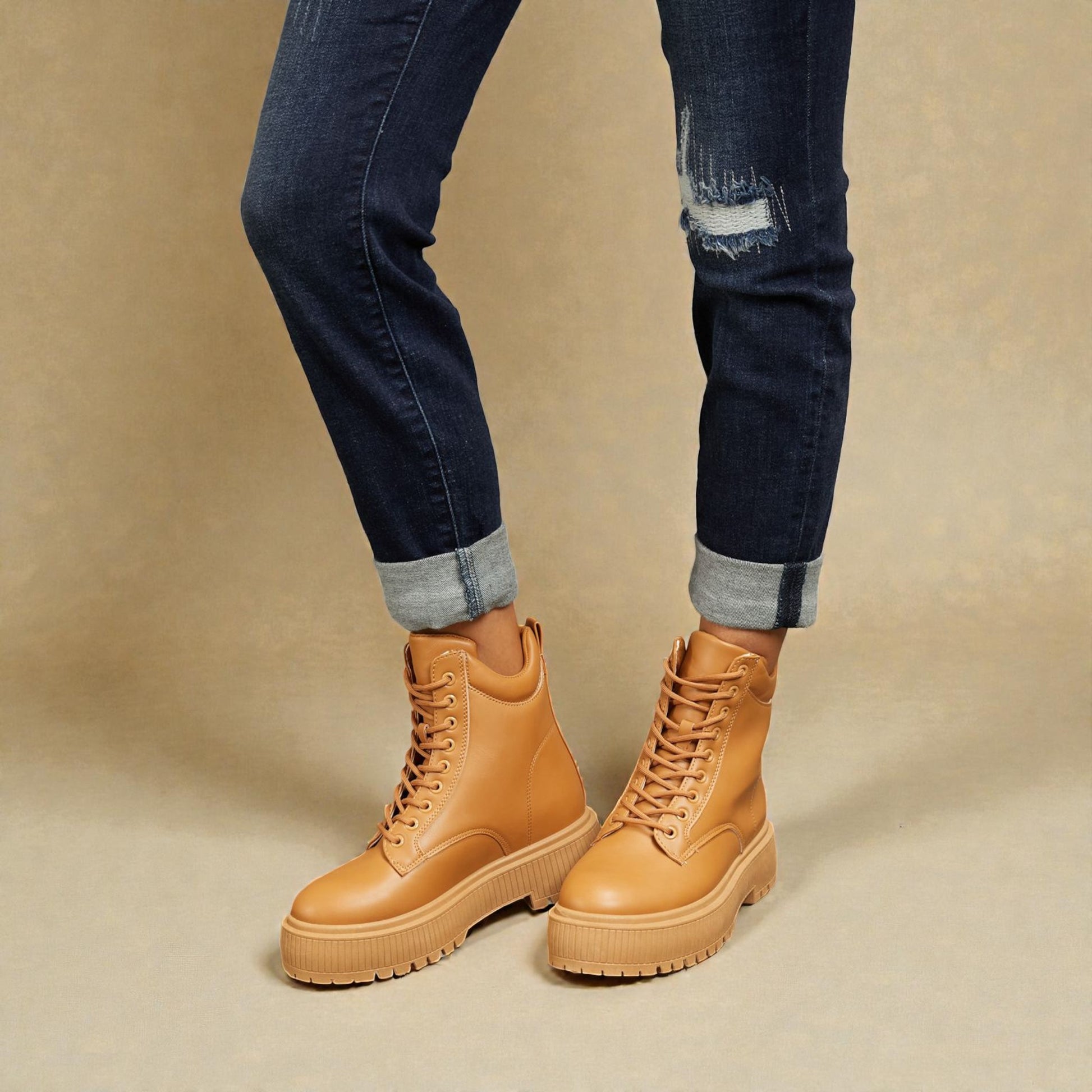 Tan boots worn with dark jeans on a beige background