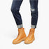 A person wearing tan lace-up platform ankle boots with dark blue ripped jeans, shown from the knees down against a plain white background.