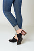 Person wearing blue jeans and black clogs on a white background