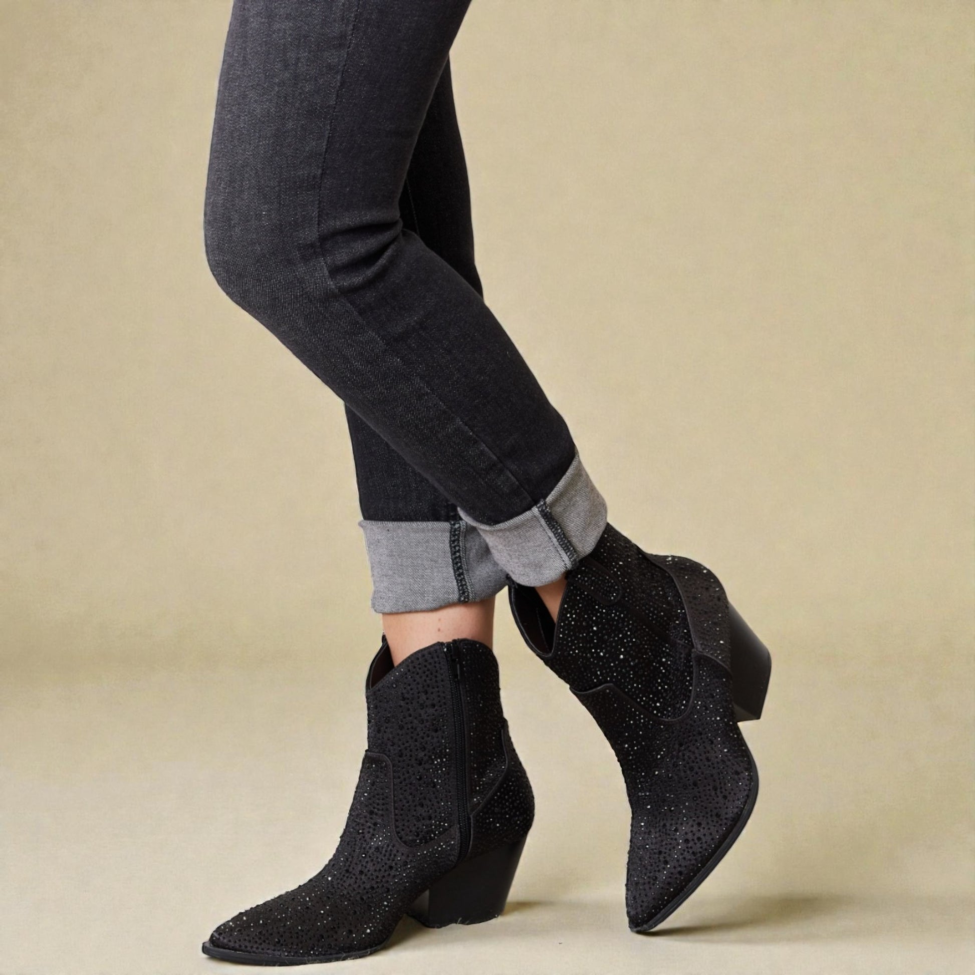 Black ankle boots worn with black pants on a beige background