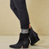 Black ankle boots worn with black jeans on a beige background