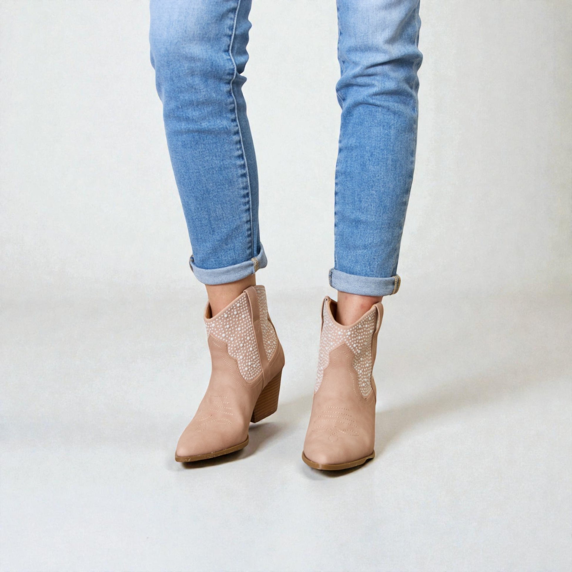 Beige ankle boots worn with light blue jeans on a white background