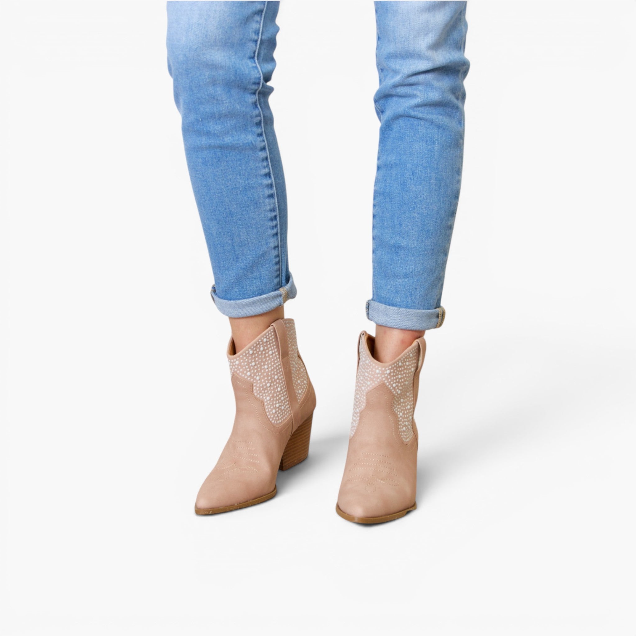 A person wearing light blue cuffed jeans and beige western-style ankle boots with glittery embellished shafts, shown against a plain white studio background.